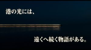夜の暗い海を背景に「港の光には、遠くへ続く物語がある。」と書かれたスライド